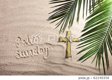 Cross and Palm Tree Leaves on sand. Palm sunday concept. Top view Cross and Palm Tree Leaves on sand. Palm sunday concept. Top view 62240356