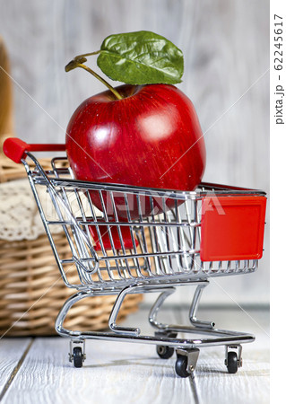 A red ripe apple lies in a shopping trolley. A red ripe apple lies in a shopping trolley. 62245617