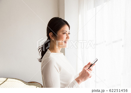 窓際でスマホを見る女性 62251456