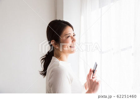 窓際でスマホを見る女性 窓際でスマホを見る女性 62251460