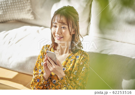 リビングでスマートフォンを見る女性 リビングでスマートフォンを見る女性 62253516