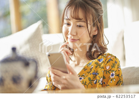 リビングでスマートフォンを見る女性 リビングでスマートフォンを見る女性 62253517