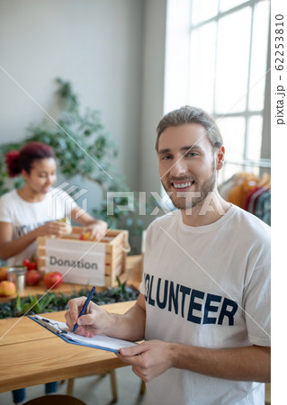 Young bearded man in a white T-shirt with a folder. Young bearded man in a white T-shirt with a folder. 62253810