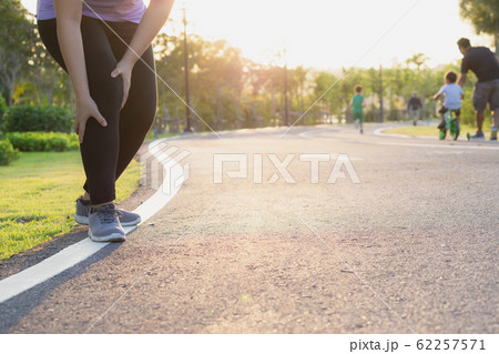 sport woman holding knee with her hands after suffering muscle injury during a running at park sport woman holding knee with her hands after suffering muscle injury during a running at park 62257571