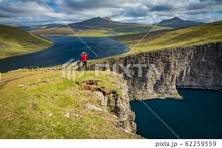 Tourists over Sorvagsvatn lake cliffs over the ocean under the clouds, Faroe Islands 62259559