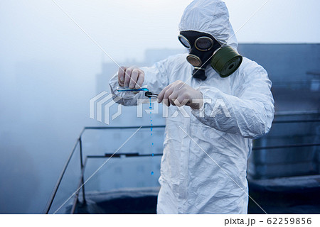 Worker scientist wearing protective coverall and gas mask doing ecological tests on the roof Worker scientist wearing protective coverall and gas mask doing ecological tests on the roof 62259856