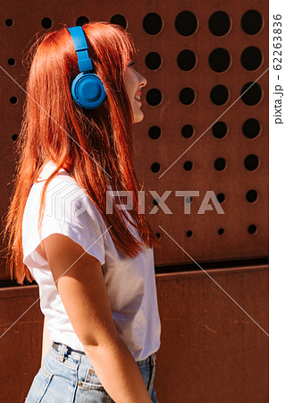 Girl listening to music on street in headphones Girl listening to music on street in headphones 62263836