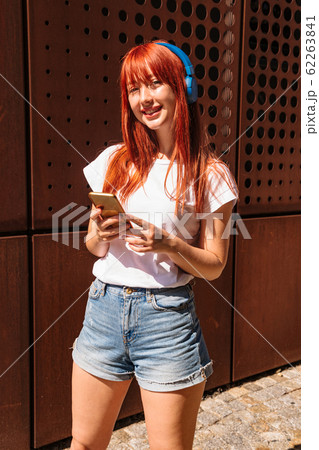 Girl with headphones looks at camera and smiles Girl with headphones looks at camera and smiles 62263841