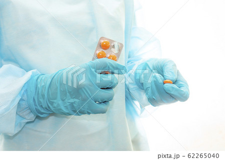Nurse in sterile gown and gloves gives pill from pack 62265040