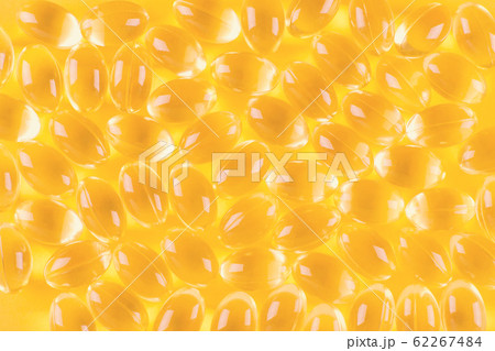 golden omega capsules on yellow background, 62267484