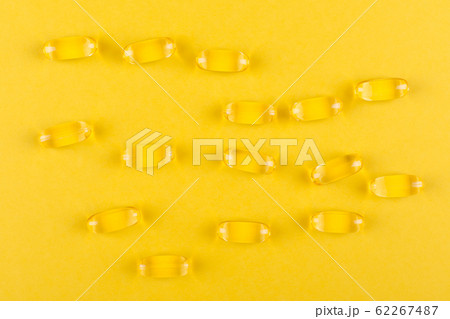 golden omega capsules on yellow background closeup golden omega capsules on yellow background closeup 62267487