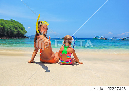 Mother, baby girl in snorkeling mask sit on sand Mother, baby girl in snorkeling mask sit on sand 62267808