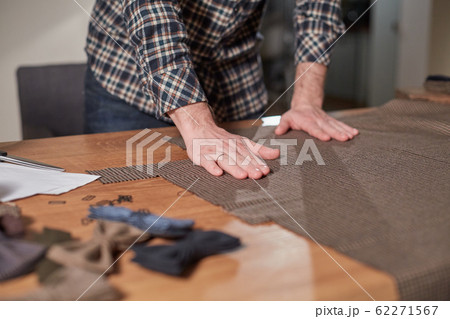 Close-up hands of Tailor, cutting wool fabric. Craftsman Makes rectangular blanks for Bow ties of woolen fabric. Work with sewing machine in a textile studio. Close-up hands of Tailor, cutting wool fabric. Craftsman Makes rectangular blanks for Bow ties of woolen fabric. Work with sewing machine in a textile studio. 62271567