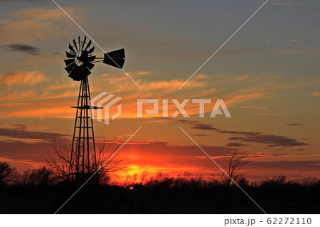 Kansas colorful Sunset with a colorful sky,tree's, and Windmill silhouettes out in the country Kansas colorful Sunset with a colorful sky,tree's, and Windmill silhouettes out in the country 62272110