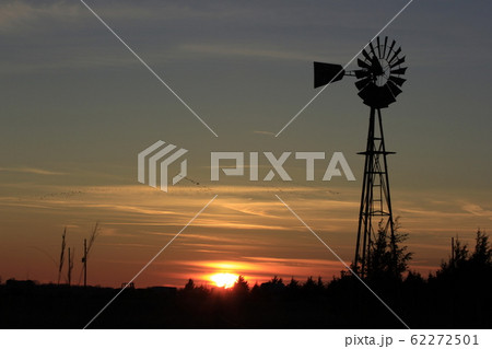 Colorful Sunset with colorful cloud's,tree's and a Windmill Silhouette out in the country in Kansas USA. Colorful Sunset with colorful cloud's,tree's and a Windmill Silhouette out in the country in Kansas USA. 62272501