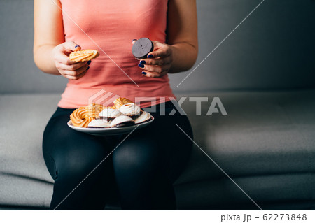 Fit woman snacking with sugary food 62273848