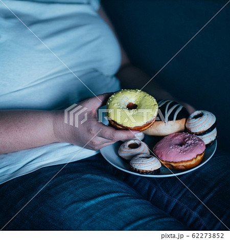 Lonely sad woman eating sweets and watching tv 62273852