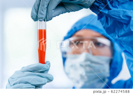 Medic in hazmat protective suit holds a test tube with a coronavirus positive blood sample from Wuhan, China. 2019 nCoV pandemic. stop coronavirus. MERS. 62274588