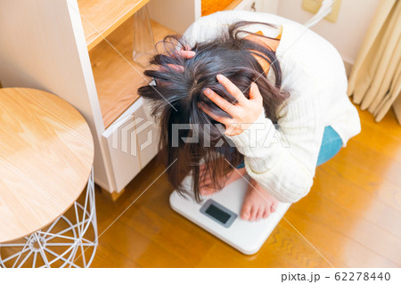 体重計に乗る女性 頭を抱える 体重計に乗る女性 頭を抱える 62278440