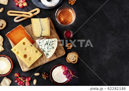 Cheese platter, shot from the top on a black background with copy space. Blue cheese, Brie, Dutch cheese and others with wine 62282186