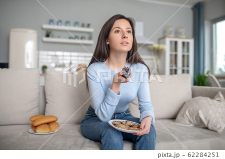 Woman eating cookies and buns near the TV Woman eating cookies and buns near the TV 62284251
