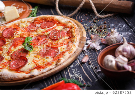 Pizza with sausage and tomatoes near spices 62287552