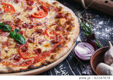 Pizza with sausages, ham, onions and tomatoes 62287678