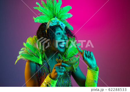 Beautiful young woman in carnival and masquerade costume on gradient studio background in neon light 62288533