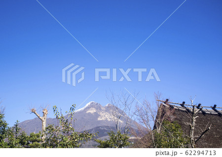 積雪の由布岳と茅葺き屋根 62294713