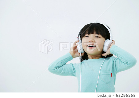 ヘッドフォンで音楽を聴いている女の子 白背景の写真素材