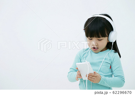 ヘッドフォンでスマートフォンの音楽を聴く女の子白背景 ヘッドフォンでスマートフォンの音楽を聴く女の子白背景 62296670