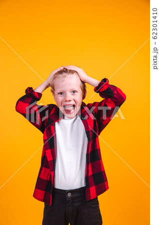 Terrified blond hair boy clutched at his head on yellow background 62301410