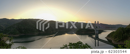 冬の日の出の羽路ダムと羽路ダム湖水橋のパノラマ風景 62303544