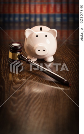 Gavel and Piggy Bank on Wooden Table With Law Books Behind Books Behind Gavel and Piggy Bank on Wooden Table With Law Books Behind Books Behind 62307346