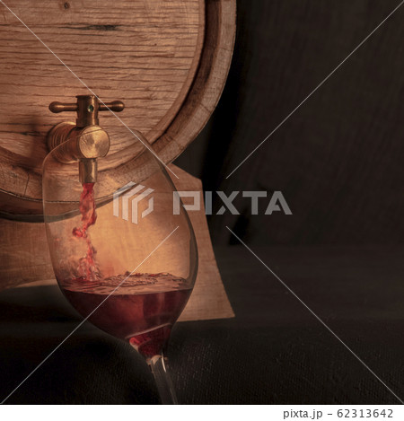Pouring wine square design template with copy space, a jet of red wine poured from an oak barrel into a glass, toned image Pouring wine square design template with copy space, a jet of red wine poured from an oak barrel into a glass, toned image 62313642