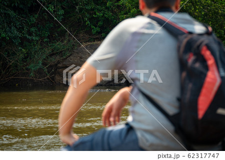 Rear view of tourist at river shore looking at crocodile 62317747