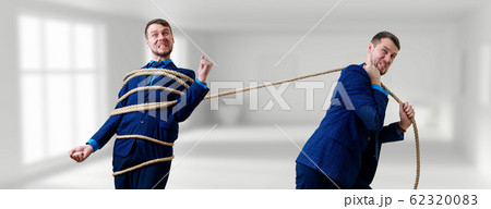Angry businessman pulls tied himself with a rope. 62320083