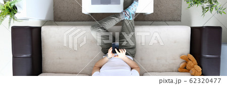 Man sit on sofa and hold modern smartphone in hand Man sit on sofa and hold modern smartphone in hand 62320477