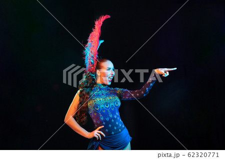 Beautiful young woman in carnival and masquerade costume in colorful neon lights on black background Beautiful young woman in carnival and masquerade costume in colorful neon lights on black background 62320771