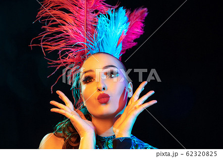 Beautiful young woman in carnival and masquerade costume in colorful neon lights on black background Beautiful young woman in carnival and masquerade costume in colorful neon lights on black background 62320825