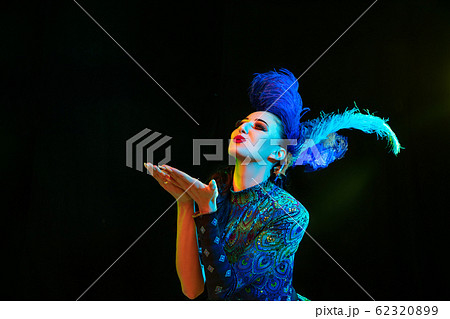 Beautiful young woman in carnival and masquerade costume in colorful neon lights on black background 62320899