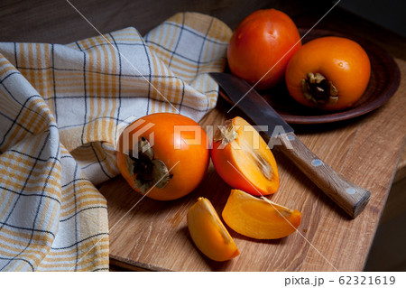 Whole ripe persimmon and sliced fruit on a wooden Whole ripe persimmon and sliced fruit on a wooden 62321619