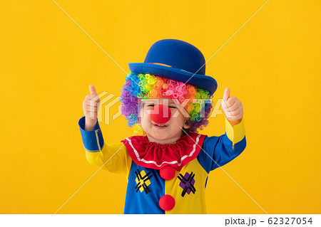 Funny kid clown playing against yellow background 62327054