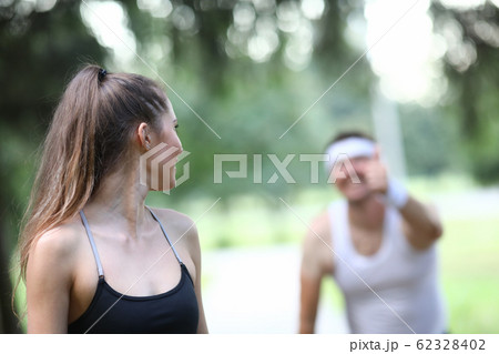 Slender girl looks back at man showing ok gesture. 62328402