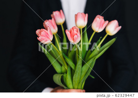 bouquet of pink tulips in men's hands in a blue suit 62329447