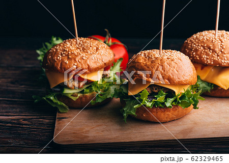 three homemade hamburgers with meat, cheese, lettuce and tomatoes 62329465
