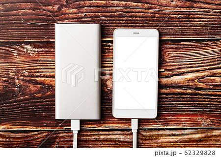 Powerbank charges a smartphone on a wooden Powerbank charges a smartphone on a wooden 62329828