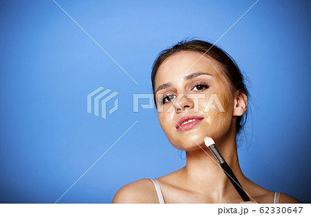 Cheerful woman applying golden mask 62330647