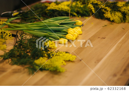 Working place of floristic. Yellow tulips lilac on wooden table Working place of floristic. Yellow tulips lilac on wooden table 62332168