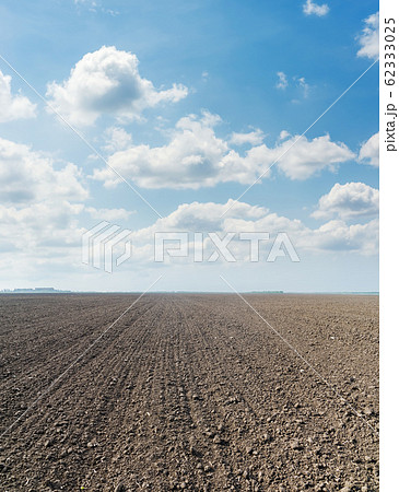 black agriculture plowed field and clouds in blue 62333025